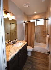 Full bathroom featuring hardwood / wood-style floors, vanity, toilet, and shower / bathtub combination with curtain