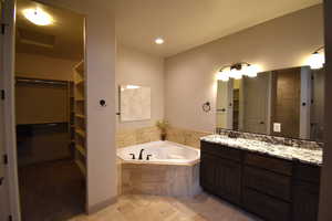 Bathroom with vanity, a relaxing tiled tub, and tile patterned floors