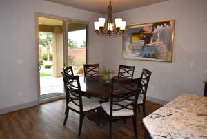 Dining space featuring dark wood-type flooring, a wealth of natural light, and an inviting chandelier