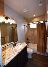 Full bathroom featuring shower / bath combo with shower curtain, hardwood / wood-style floors, vanity, and toilet