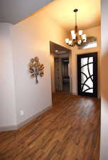 Foyer entrance with dark hardwood / wood-style flooring and an inviting chandelier