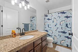 Bathroom with toilet, vanity, tile patterned floors, and curtained shower