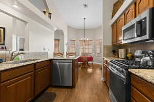 Kitchen with sink, an inviting chandelier, kitchen peninsula, decorative light fixtures, and appliances with stainless steel finishes