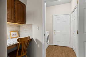 Clothes washing area featuring washer / clothes dryer and light hardwood / wood-style floors