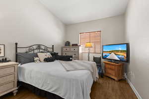 Bedroom with dark wood-type flooring and vaulted ceiling