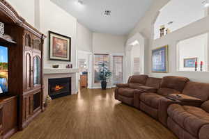 Living room with a tile fireplace, a towering ceiling, dark wood-type flooring, and a healthy amount of sunlight