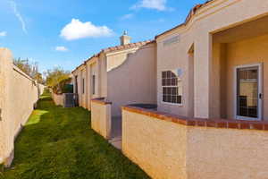 View of side of home featuring central AC unit and a yard