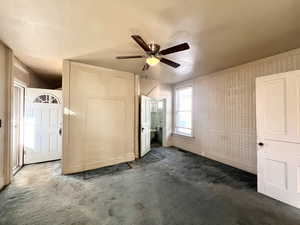 Unfurnished bedroom featuring ceiling fan and dark carpet