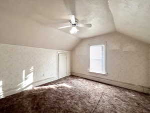 Additional living space with a textured ceiling, ceiling fan, carpet floors, and vaulted ceiling