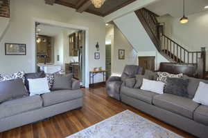 Living room featuring an inviting chandelier, crown molding, sink, beamed ceiling, and dark hardwood / wood-style flooring