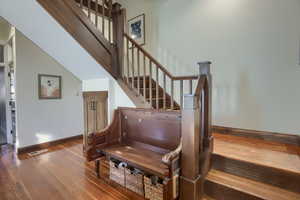 Staircase with a towering ceiling and hardwood / wood-style flooring