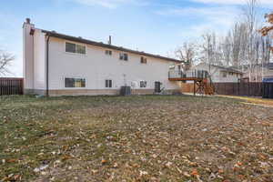 Rear view of house featuring a wooden deck, a yard, and cooling unit