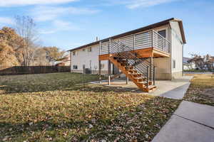 Back of house featuring central air condition unit, a yard, a patio, and a deck