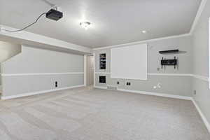 Cinema room with carpet flooring, ornamental molding, and a textured ceiling