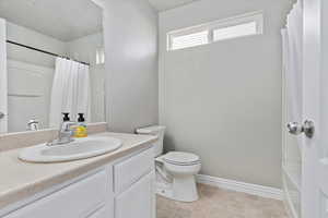 Full bathroom with shower / bath combo with shower curtain, vanity, and toilet