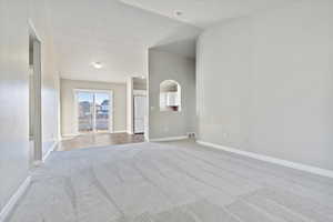 Unfurnished room featuring carpet flooring and lofted ceiling