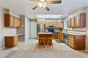 Kitchen with backsplash, a skylight, stainless steel appliances, sink, and a kitchen island