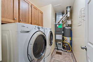 Clothes washing area featuring cabinets, gas water heater, and independent washer and dryer