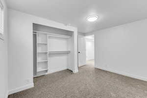 Unfurnished bedroom with carpet flooring, a textured ceiling, and a closet