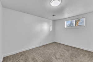 Empty room featuring carpet and a textured ceiling