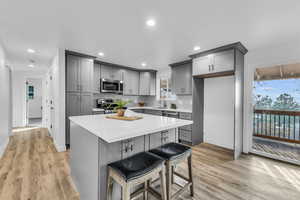 Kitchen featuring appliances with stainless steel finishes, light wood-type flooring, sink, a center island, and gray cabinets