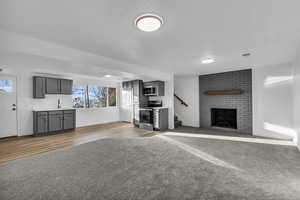 Unfurnished living room with sink, light hardwood / wood-style floors, and a brick fireplace