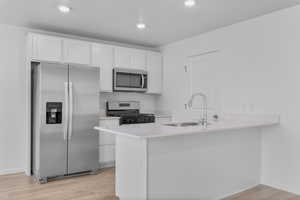 Kitchen with white cabinets, light wood-type flooring, sink, and appliances with stainless steel finishes