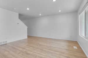 Empty room with a textured ceiling and light hardwood / wood-style flooring