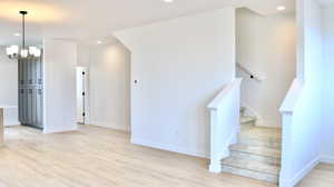 Stairway with wood-type flooring and an inviting chandelier