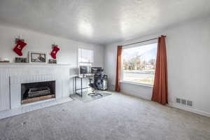 Carpeted living room with a textured ceiling and a brick fireplace