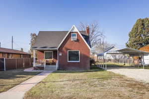 View of front of house with a porch, cooling unit, a carport, and a front lawn