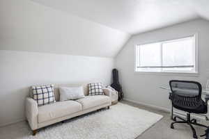 Home office featuring light colored carpet and lofted ceiling