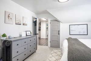 Bedroom featuring light carpet and vaulted ceiling