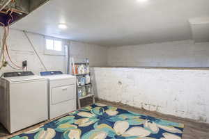 Laundry area featuring wood-type flooring and washing machine and clothes dryer