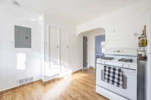 Kitchen featuring white gas range oven, electric panel, and light hardwood / wood-style floors