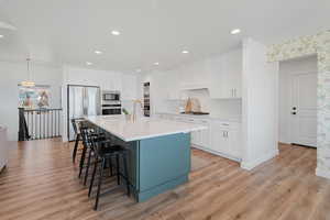 Kitchen with built in appliances, sink, white cabinets, and custom exhaust hood