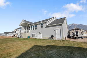 Rear view of property with a mountain view and a yard