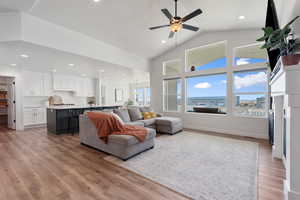 Living room featuring ceiling fan, light wood-type flooring, and vaulted ceiling