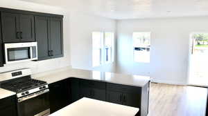 Kitchen with kitchen peninsula, appliances with stainless steel finishes, and light wood-type flooring