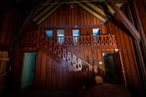 Staircase featuring beam ceiling, high vaulted ceiling, and wooden walls