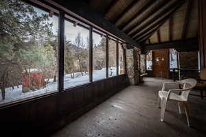 Unfurnished sunroom with wood ceiling and lofted ceiling with beams