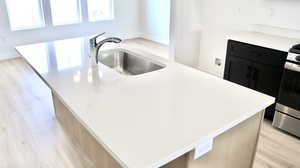 Kitchen with a center island, sink, stainless steel stove, and light hardwood / wood-style flooring