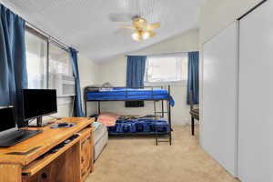 Bedroom with light colored carpet, vaulted ceiling, ceiling fan, and cooling unit