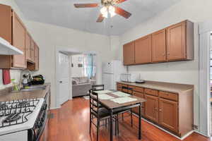 Kitchen featuring light wood-type flooring, white appliances, ceiling fan, and sink