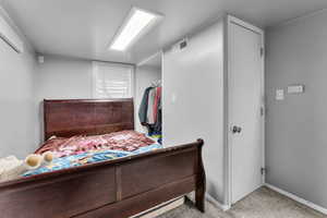 Bedroom featuring a wall mounted air conditioner and light carpet