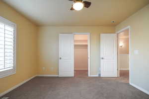 Unfurnished bedroom with carpet flooring, a walk in closet, ceiling fan, and a closet