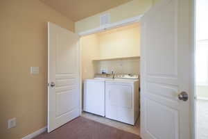 Laundry area with light carpet and washer and clothes dryer