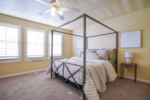 Bedroom with a textured ceiling, carpet floors, and ceiling fan