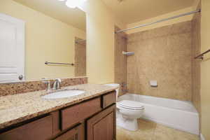 Full bathroom with vanity, tile patterned floors, tiled shower / bath combo, toilet, and a textured ceiling