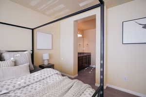 Bedroom featuring connected bathroom, dark carpet, and a textured ceiling